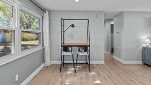 Una habitación con literas, un escritorio con silla, una lámpara y un ventanal con cortinas.