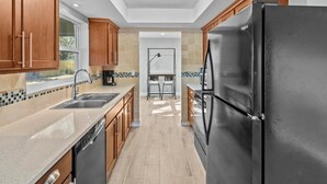 Una cocina moderna con armarios de madera, un refrigerador negro y un salpicadero de azulejos.