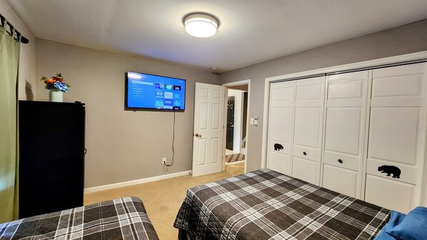 Un dormitorio con dos camas, un televisor en la pared y un armario.