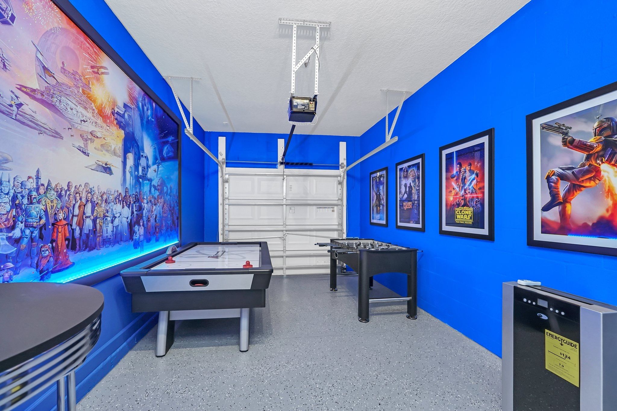 A room with a pool table, a foosball table, and Star Wars themed decorations.