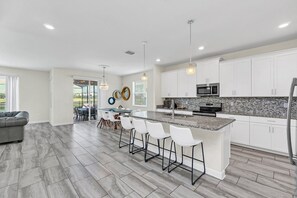 A modern kitchen with white cabinets, a granite countertop, and stainless steel appliances.