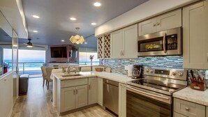 A modern kitchen with stainless steel appliances, a large island, and a view to the outside.