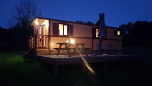 A small, single-story cabin with a wooden deck, a picnic table, and a covered seating area. - La Pouypardin, a caravan for a cosy stay (CONDOM)