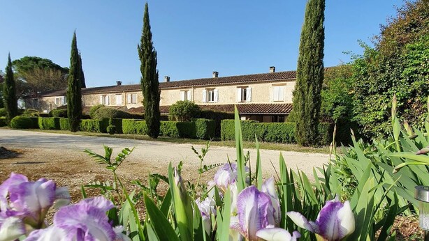 A building with a symmetrical facade, a gravel driveway, and neatly trimmed hedges. - La Pouypardin, a caravan for a cosy stay (CONDOM)