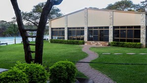 A modern building with a stone facade, large windows, and a paved pathway leading to the entrance. - Tiffany s Canyon lodge (Kafue)