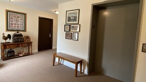 A hallway with a wooden bench, a console table with decorative items, and framed pictures on the wall. - Country Inn of Hazlet (Hazlet)