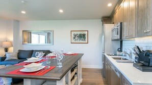 A modern kitchen with wooden cabinets, a built-in microwave, and a dining area with a table set for four. - 1 bedroom Penthouse at the Peaks Resort and Spa (Mountain Village)