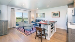 A modern kitchen with a dining area, a large window with curtains, and a view of the outdoors. - 1 bedroom Penthouse at the Peaks Resort and Spa (Mountain Village)