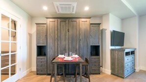 A dining area with a table set for two, flanked by wooden cabinets and a television on a stand. - 1 bedroom Penthouse at the Peaks Resort and Spa (Mountain Village)