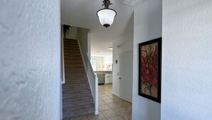 Un pasillo con una escalera que lleva a una zona de cocina.