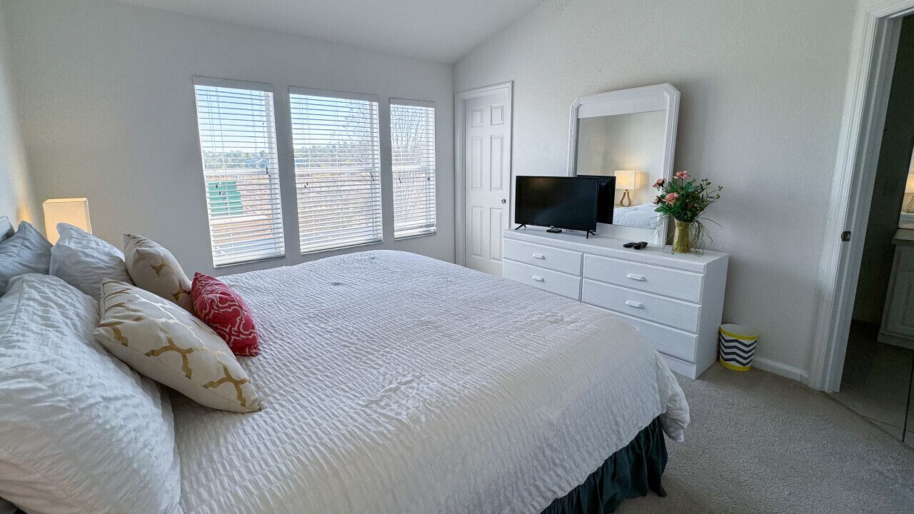 Un dormitorio con una cama grande, un aparador, un televisor y un espejo.