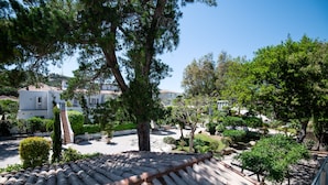 A courtyard with a tiled roof, surrounded by trees and a small garden. - Charming Suite - La Serra (Calvi)