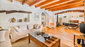 Un salón amplio con techo de madera, un sofá, una mesa de centro y una mesa de comedor con sillas.