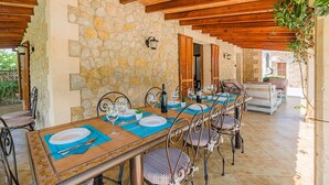 An outdoor dining area with stone walls, wooden beams, and metal chairs. - BARRETAS Ref. VP52 (Alcúdia)