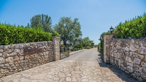 A stone pathway leading to a gate with a sign, surrounded by greenery and trees. - BARRETAS Ref. VP52 (Alcúdia)