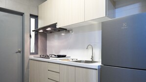 Una cocina moderna con armarios de madera clara, un lavamanos de acero inoxidable y una estufa empotrada.