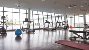 Un gimnasio amplio con ventanas grandes, cintas de correr y diversos equipos de ejercicio.
