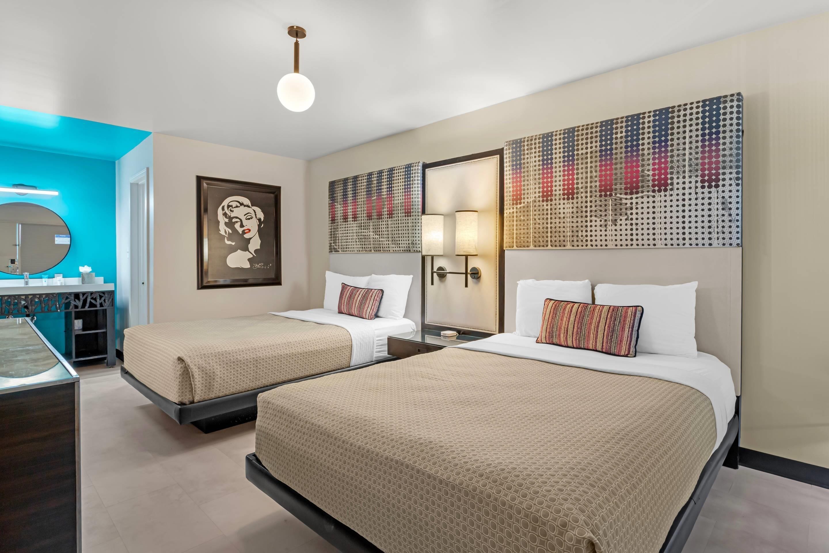 Een hotelkamer met twee bedden, een bureau, een spiegel en kunst aan de muren.