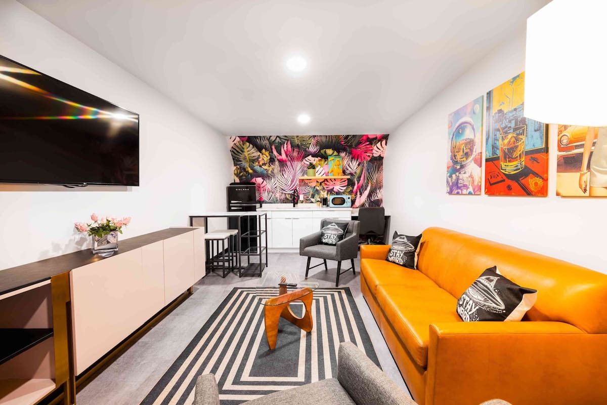 A compact living space with a kitchenette, a sofa, a coffee table, and a flat-screen TV.