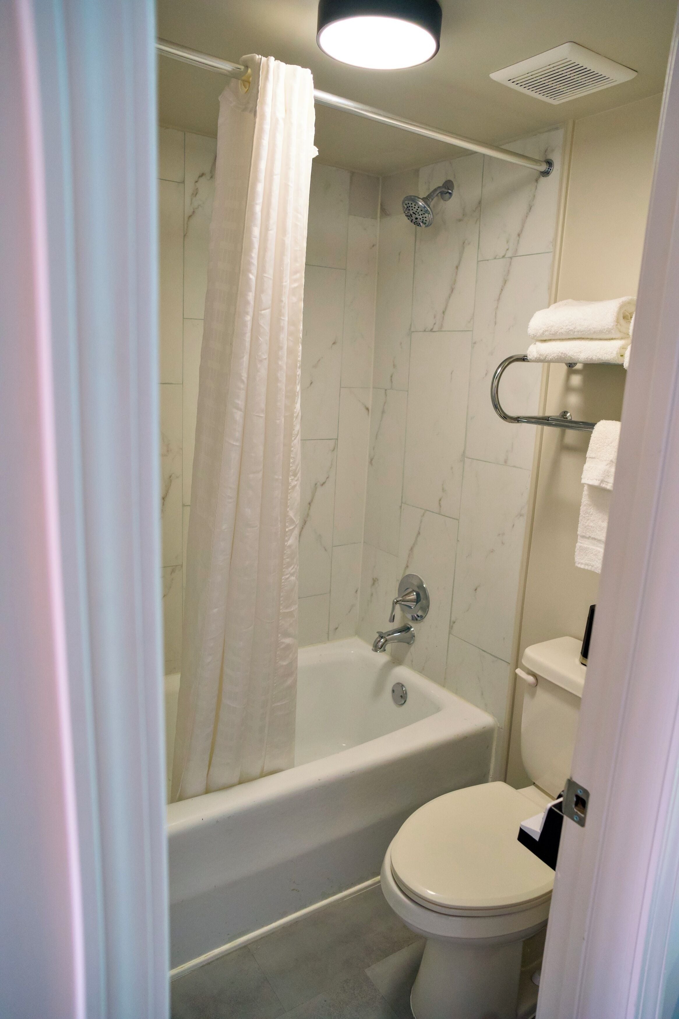 A bathroom with a bathtub, toilet, and shower curtain.