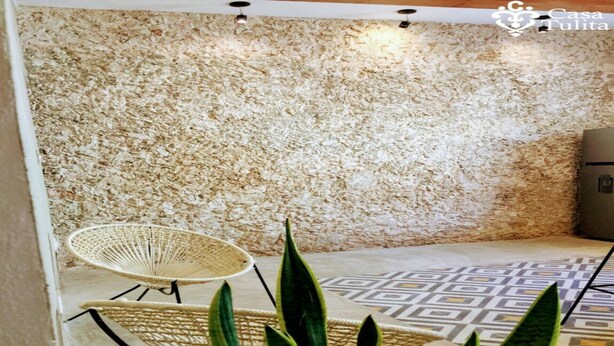 A room with a textured wall, a woven chair, and a patterned floor. - Premium Suite near Cathedral - 2 Min walk (Valladolid)