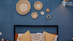 A bedroom with a blue wall, a bed with two pillows, and a bedside table with a remote control and a candle. - Premium Suite near Cathedral - 2 Min walk (Valladolid)