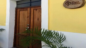 A wooden door with a metal handle, a round sign with 'Casa Tulita' on a yellow wall, and a potted plant in front. - Premium Suite near Cathedral - 2 Min walk (Valladolid)