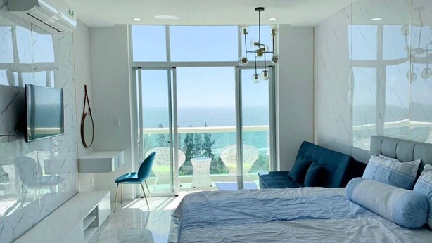 Een moderne slaapkamer met een groot bed, een televisie en uitzicht op de oceaan.