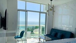 Een moderne hotelkamer met een grote schuifglazen deur naar een balkon met uitzicht op zee.