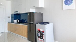 Een moderne keuken met witte kasten, een roestvrijstalen koelkast en een blauw aanrecht.