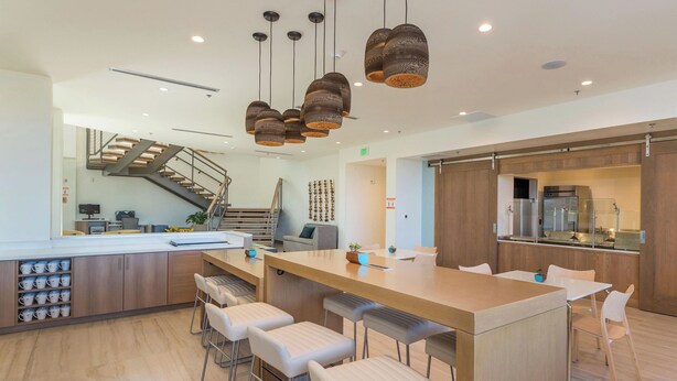 A modern kitchen with a central island, bar stools, and a staircase leading to an upper level. - Element by Marriott Denver International Airport (Denver)