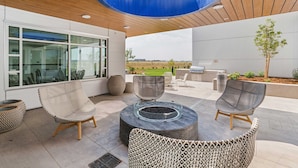 An outdoor patio area with wicker furniture, a fire pit, and a view of the landscape. - Element by Marriott Denver International Airport (Denver)