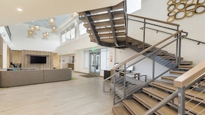 A spacious lobby with a modern staircase, a reception area, and a large flat-screen TV. - Element by Marriott Denver International Airport (Denver)