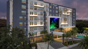 Un hotel moderno con un llamativo letrero 'element by Westin', varios pisos y una gran pantalla iluminada que muestra una imagen verde.