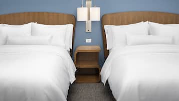 A hotel room with two beds, a nightstand, and a wall-mounted lamp.