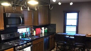 A kitchen with a gas stove, microwave, and oven, wooden cabinets, a tiled floor, and a window with blinds. - 15 mins walk to The old market area,  Its called Easy peasy (Omaha)
