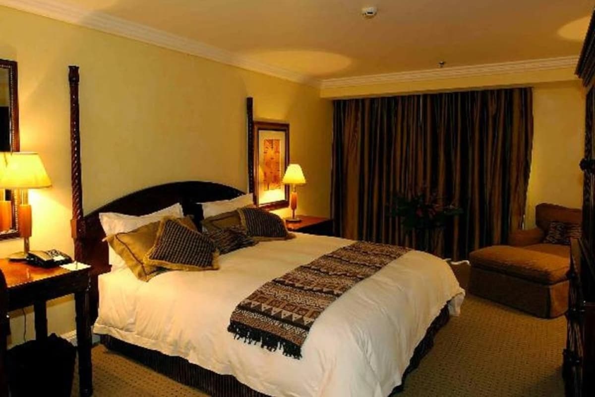 Een hotelkamer met een groot bed, twee nachtkastjes met lampen, een stoel en een gordijn.
