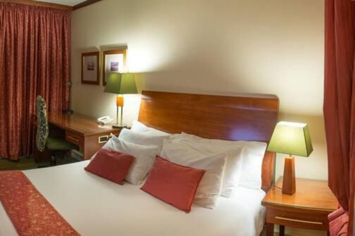 A hotel room with a bed, a desk, a chair, a television, and a curtain.