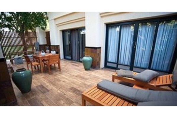 Une terrasse extérieure avec des meubles en bois, un grand vase vert et une table en bois.