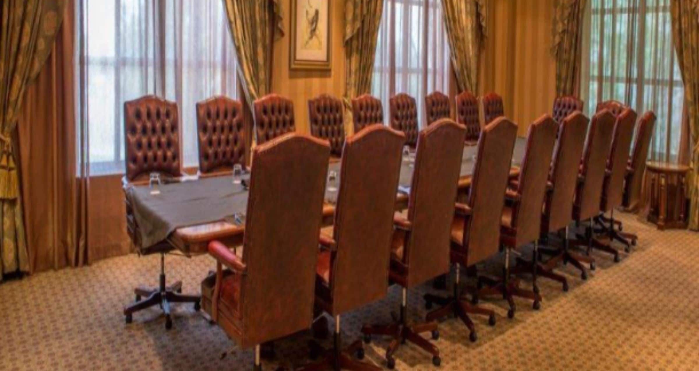 A conference room with a long table and multiple chairs.
