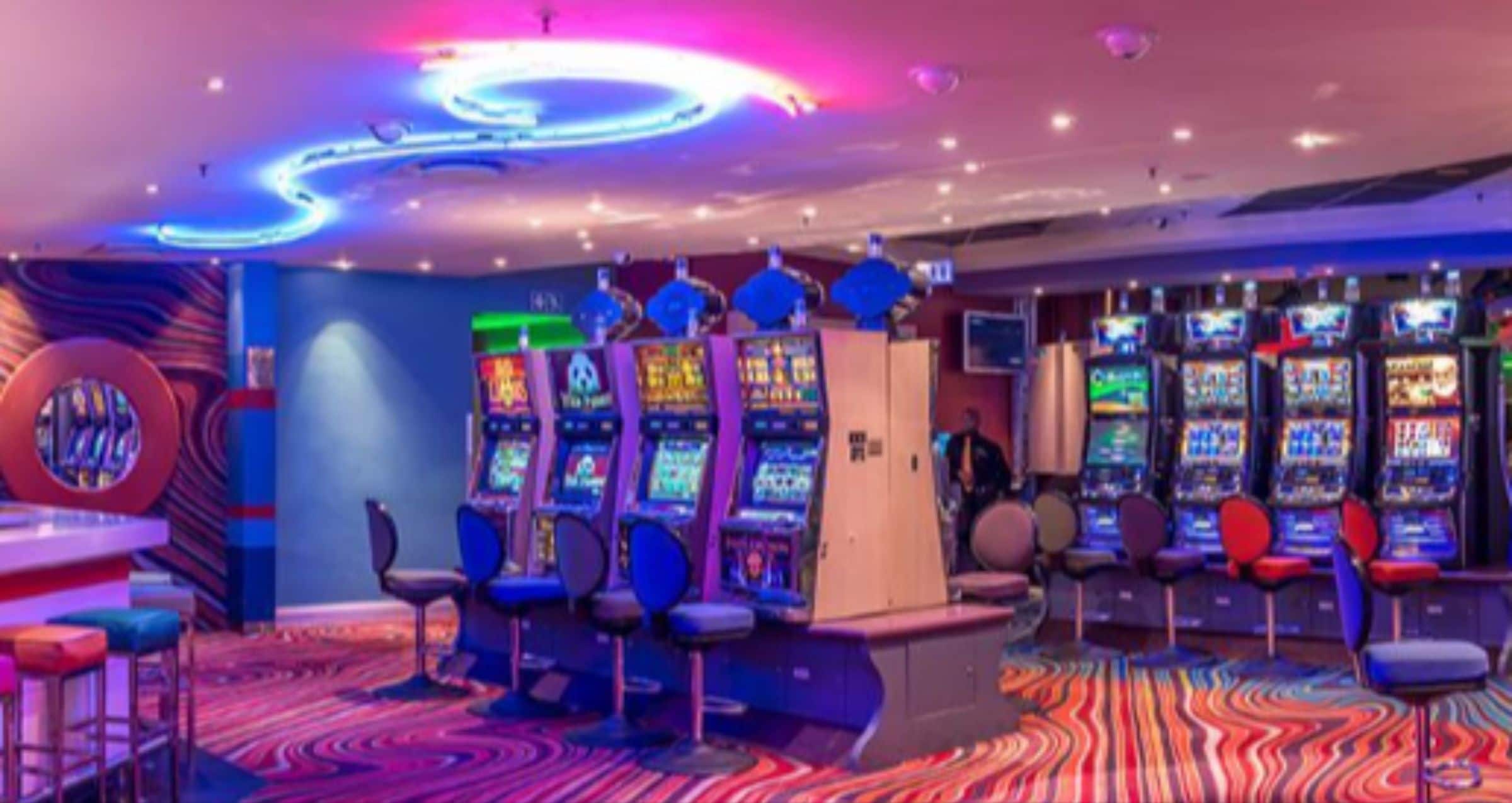 A gaming arcade with multiple arcade machines, bar stools, and a vibrant, colorful carpet.