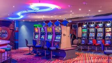 A gaming arcade with multiple arcade machines, bar stools, and a vibrant, colorful carpet.