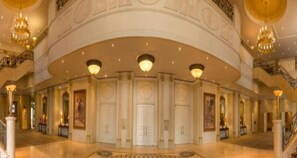 Een statige lobby met een gebogen plafond, meerdere deuren en kroonluchters.