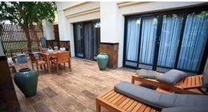 An outdoor patio with wooden furniture, a large green vase, and a wooden table. - Peermont Walmont Ambassador at the Grand Palm (Gaborone)