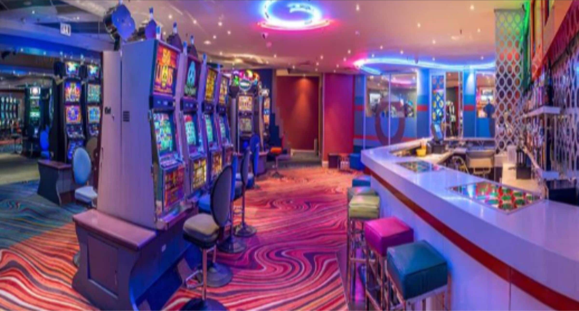 A casino with slot machines, a bar area, and a vibrant carpet.