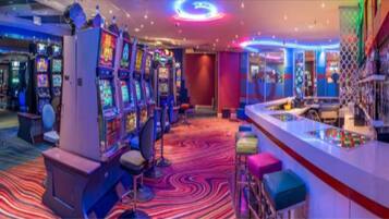 A casino with slot machines, a bar area, and a vibrant carpet.
