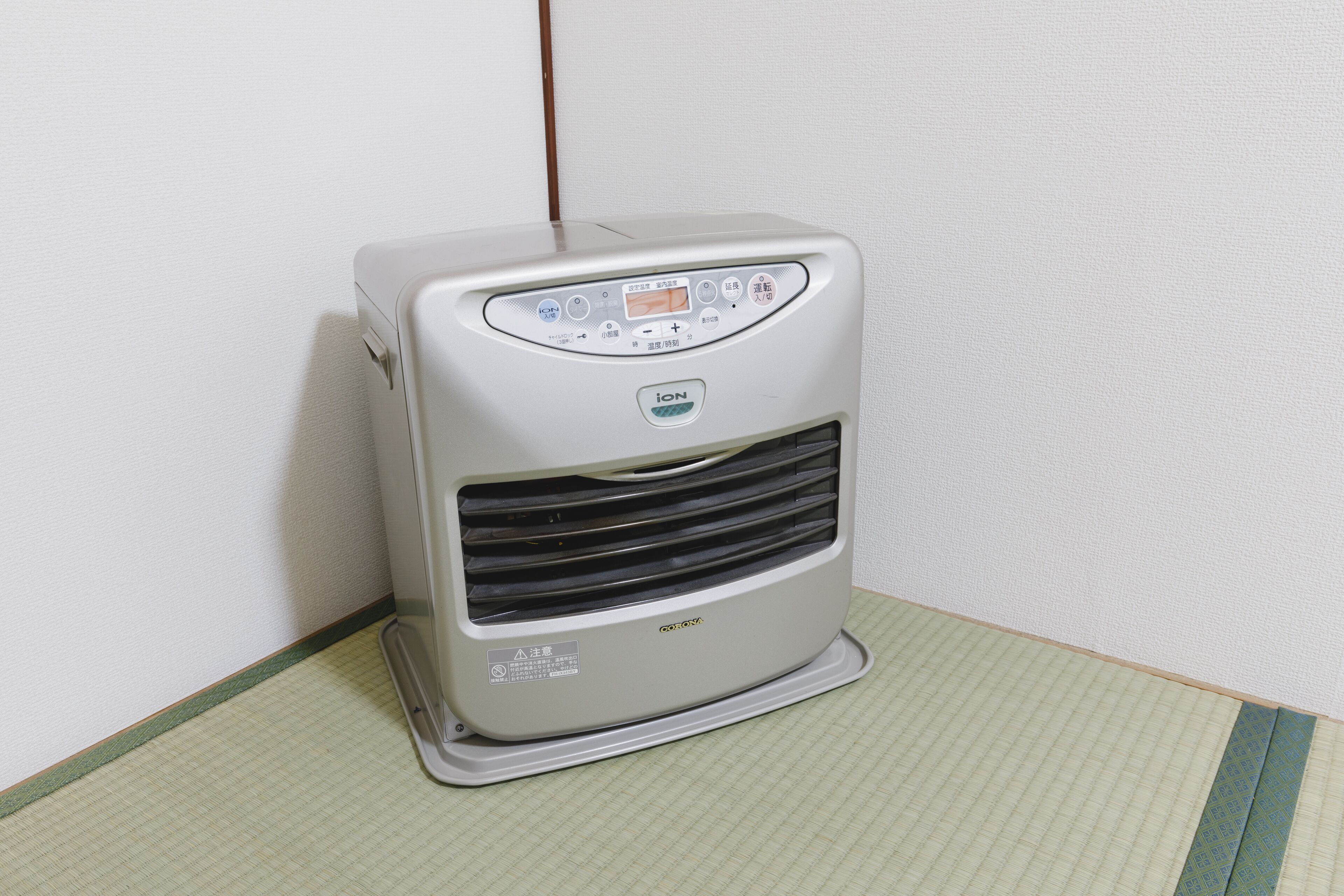 Een draagbare airconditioner met een bedieningspaneel, staand op een geruit kleed voor een effen muur.
