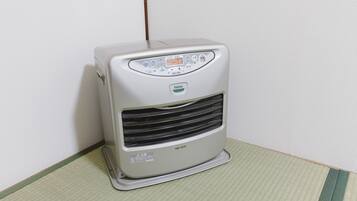 Een draagbare airconditioner met een bedieningspaneel, staand op een geruit kleed voor een effen muur.