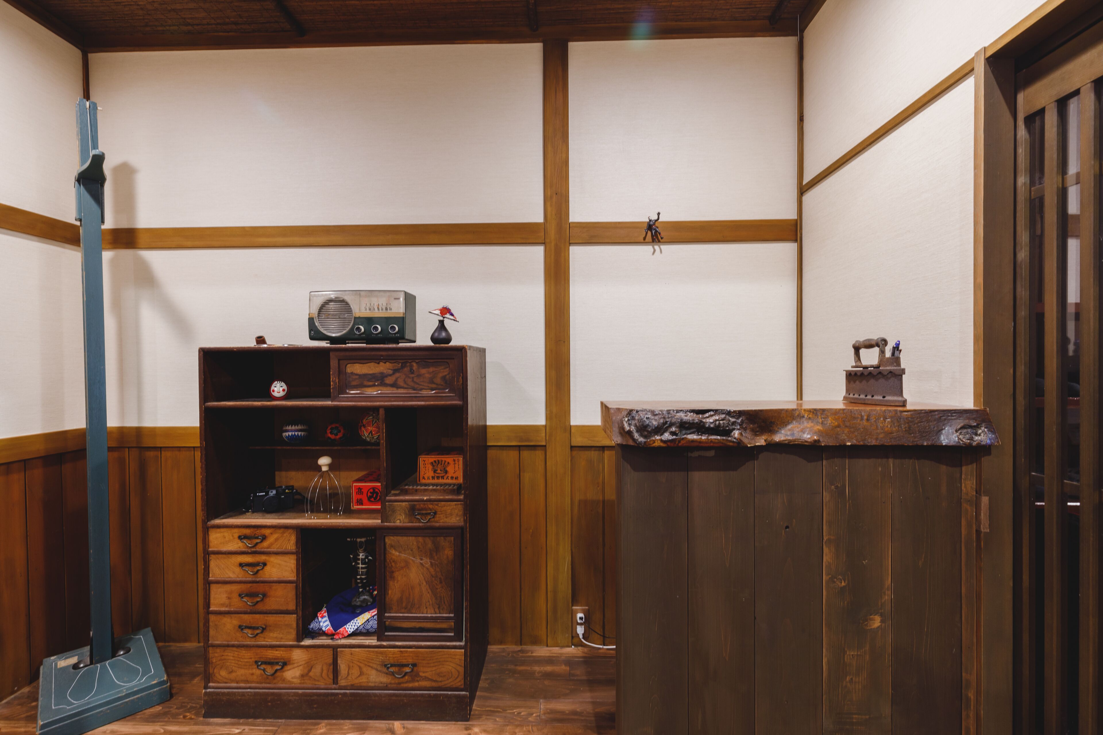 A traditional Japanese room with tatami flooring, a wooden cabinet with various items, and a wooden counter.
