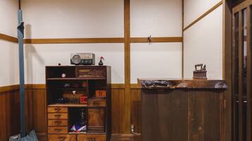 A traditional Japanese room with tatami flooring, a wooden cabinet with various items, and a wooden counter.